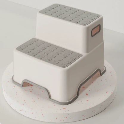 Gray and white 2-tier step stool for kids showing textured slip-resistant steps and safety rubber feet.