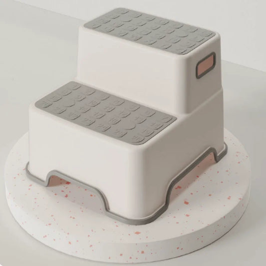 Gray and white 2-tier step stool for kids showing textured slip-resistant steps and safety rubber feet.
